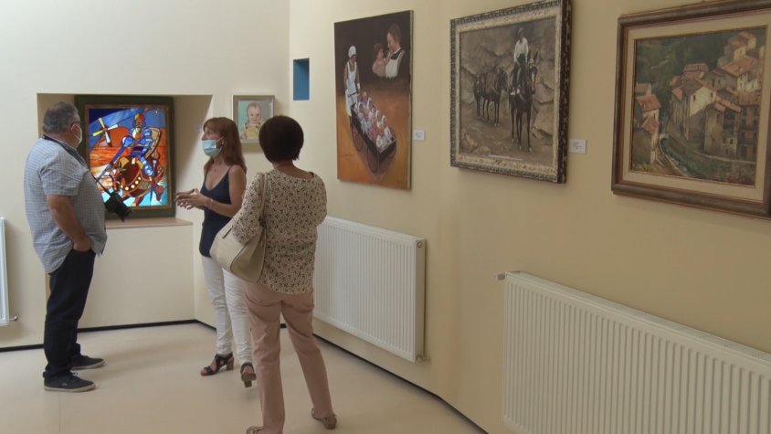 Tres persones observant algunes de les obres d'art del pintor Jacint Enfruns