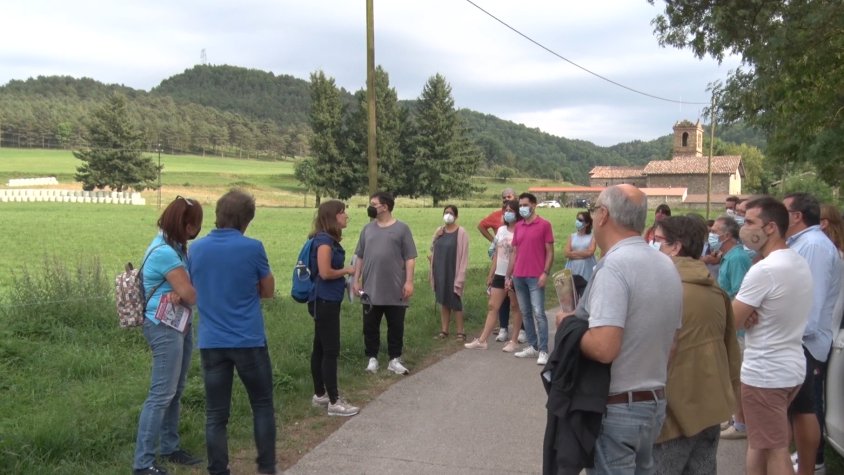 Els participants escoltant les explicacions de la guia de l'activitat amb l'església de Sant Pau Vell al fons
