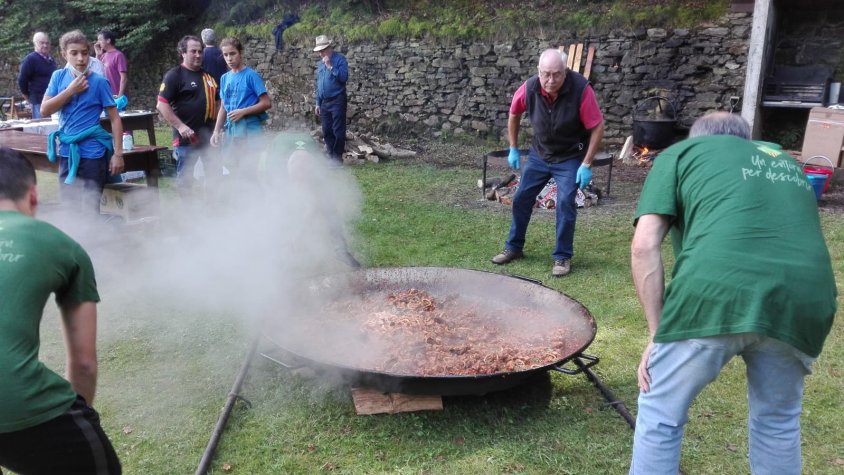 Diversos voluntaris porten la paella per a més de 400 persones lluny del foc