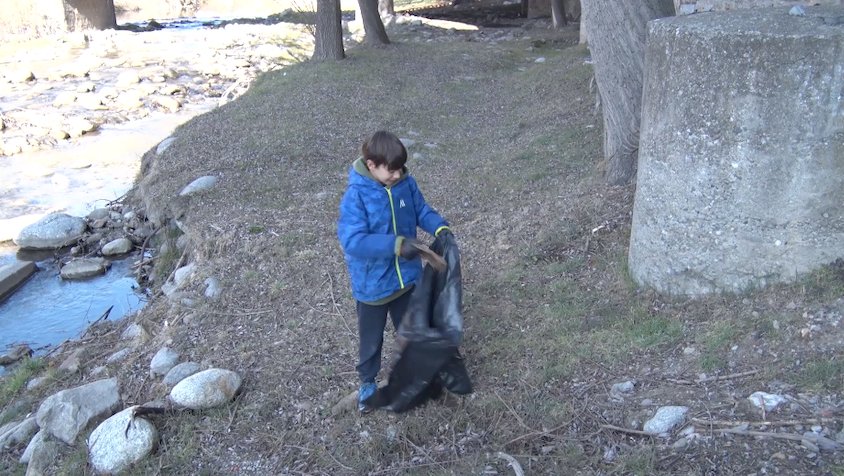 Un dels participants recollint brossa de la llera del riu a Ripoll