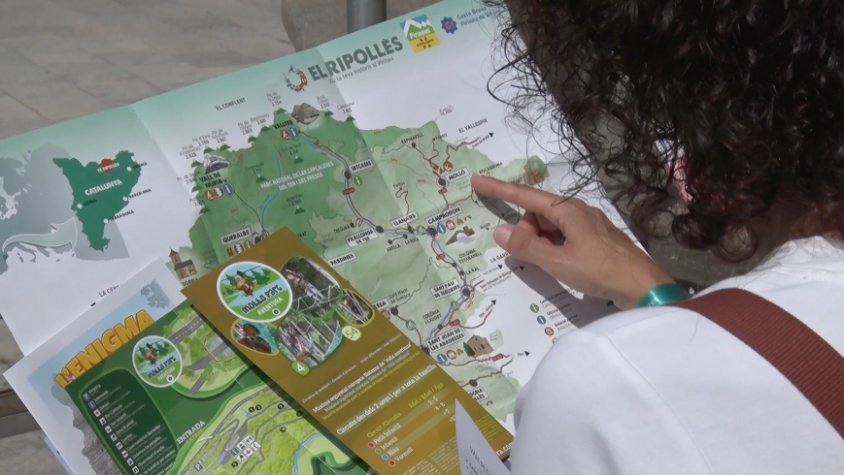 Una família consulta un mapa de la comarca a l'entrada de l'oficina de turisme de Ripoll